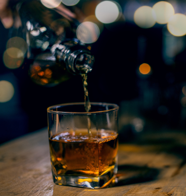 glass of whiskey and ice on wooden table